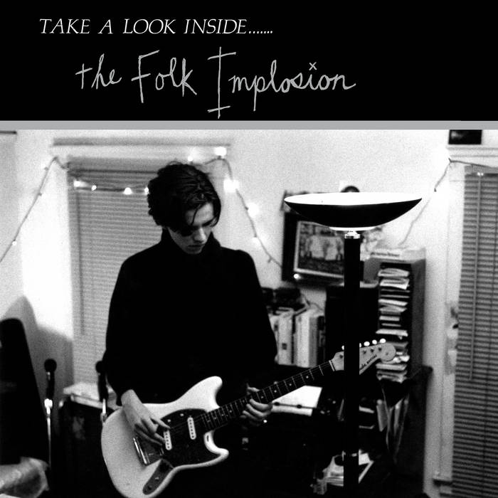 Black and white image of a person with glasses playing an electric guitar in a room with bookshelves and string lights. Text at the top reads "TAKE A LOOK INSIDE....... the Folk Implosion - Take a Look Inside.... album from Tandem Coffee Roasters.