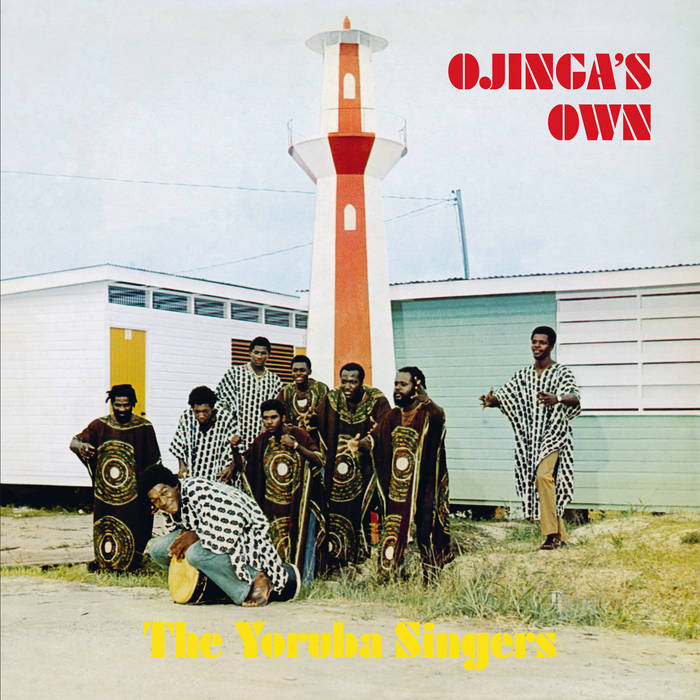 Album cover featuring nine members of The Yoruba Singers dressed in patterned traditional attire, posing in front of a red and white lighthouse. The debut album title "Yoruba Singers - Ojinga’s Own" is written in red, while the brand name "Tandem Coffee Roasters" is in yellow at the bottom.