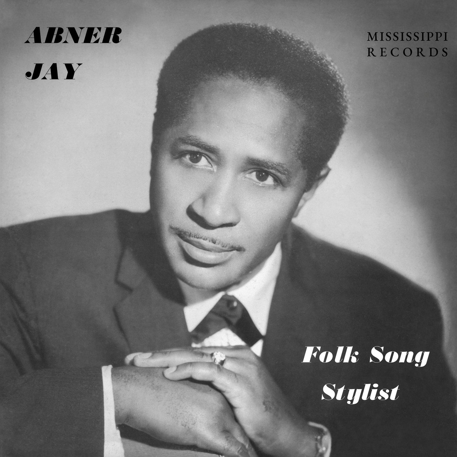 The black and white album cover for "Folk Song Stylist" showcases a portrait of Abner Jay, donning a suit and tie while resting his chin on his hand. The cover prominently features the text "Abner Jay" and highlights the brand "Tandem Coffee Roasters," along with the album title "Folk Song Stylist.